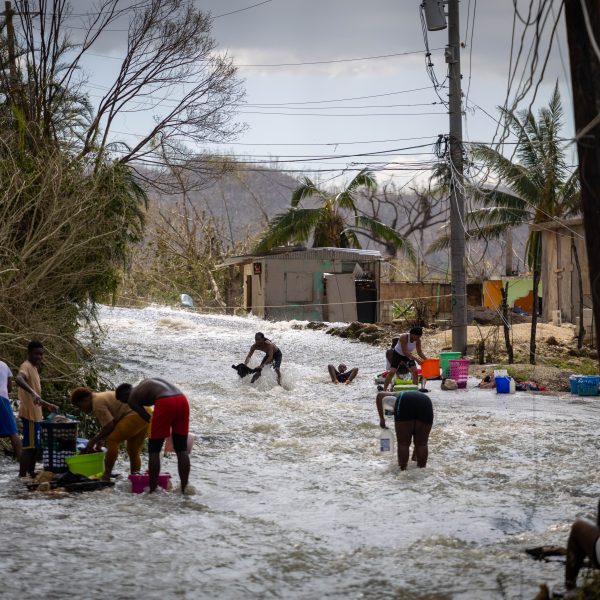 Without running water, residents in St. Elizabeth wash in the street using water brought by the hurricane