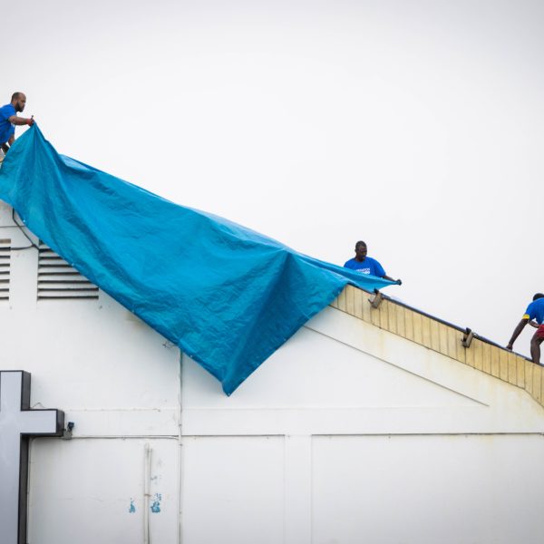 Relief workers covering a roof with tarpaulin